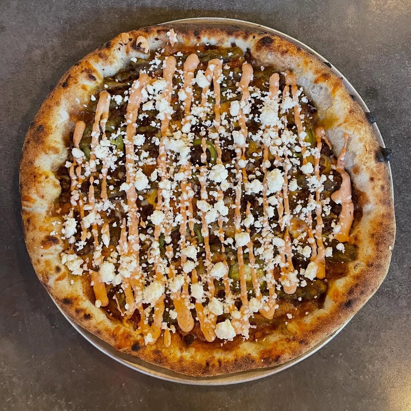 Refried beans, Mexican cheese blend, ground beef, pickled jalapeño, roasted tomato salsa, chipotle cream sauce, cotija cheese.